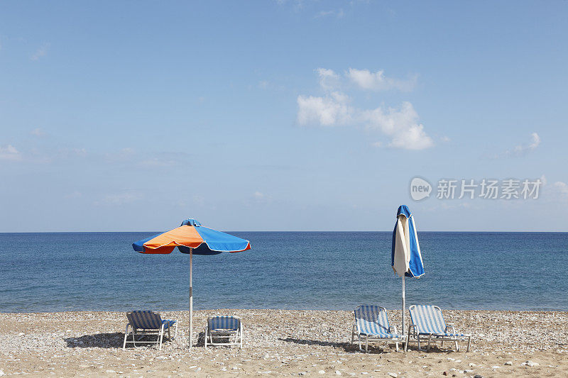 两把彩色雨伞和四个条纹日光浴床Latsi海滩塞浦路斯