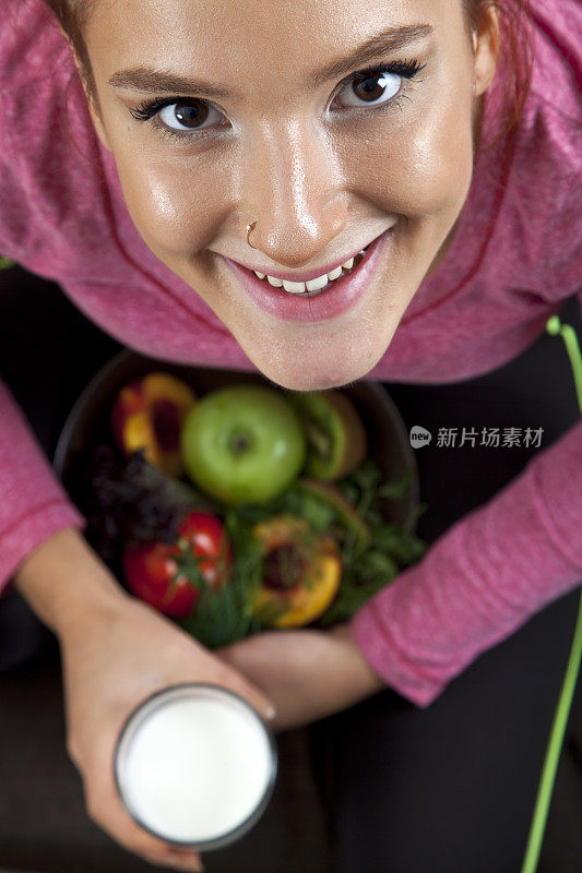 年轻女子端着一盘水果和蔬菜