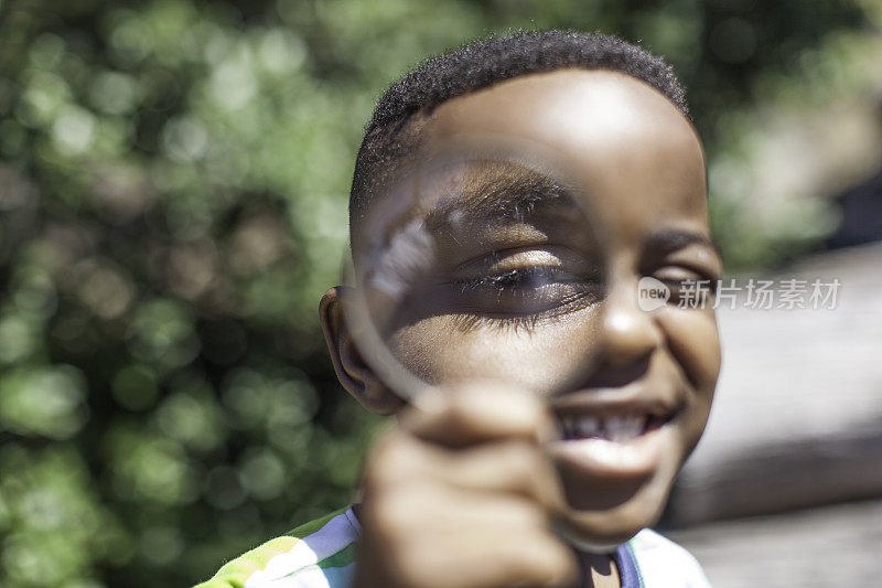 非洲男孩透过放大镜对着镜头微笑