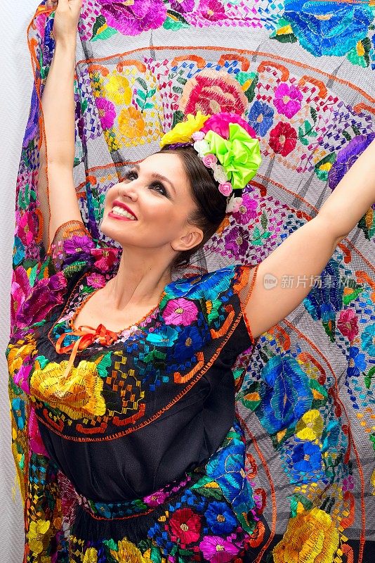 美丽的微笑的墨西哥妇女在传统的墨西哥服装，举起裙子作为背景像孔雀