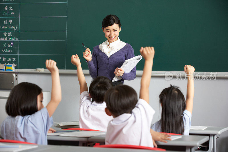 亚洲老师和学生在教室里举起手臂