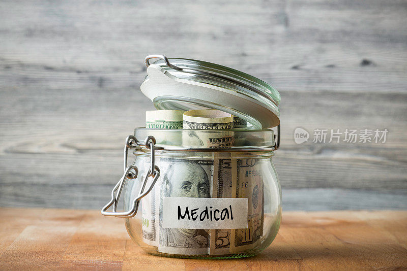 在木制背景上孤立的玻璃罐中的美元。为医疗省钱。