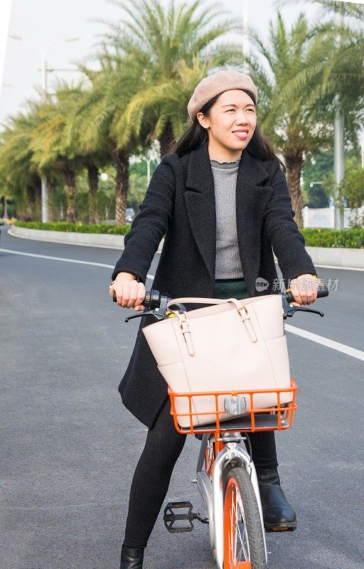 亚洲办公室女士骑自行车穿过市区