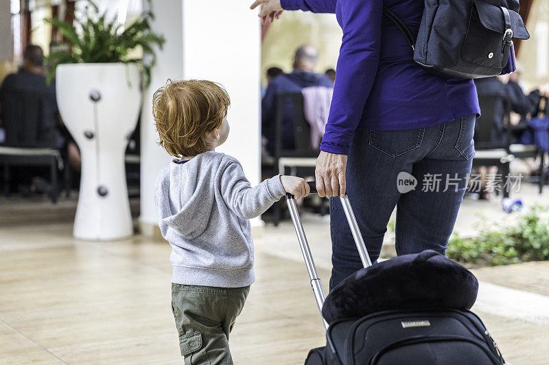 母亲或祖母和男婴带着行李箱在机场散步