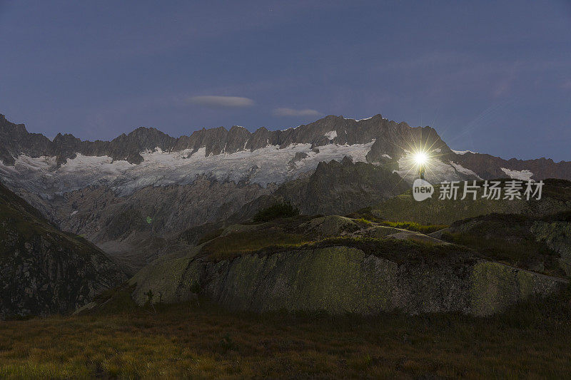 一个带着大灯的阿尔卑斯人站在瑞士阿尔卑斯山令人叹为观止的山景中