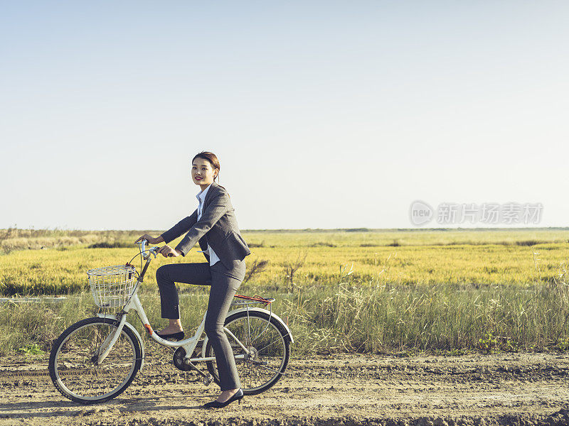 一个年轻的女商人坐在乡下的bicyale上的肖像