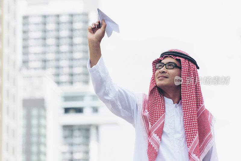 穆斯林商人手持纸飞机在城市里，自由经营理念。