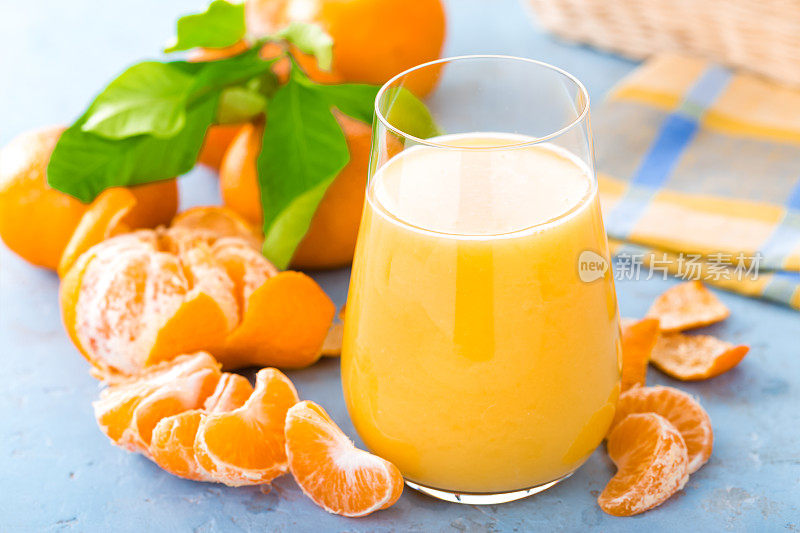 橘子，去皮的橘子和橘子汁在玻璃杯里。橘子汁和带叶子的新鲜水果。