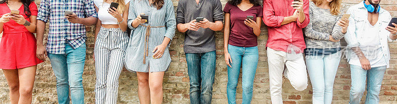 一群朋友看智能手机-青少年沉迷于新技术趋势-青年的概念，技术，社会和友谊-主要集中在中心手