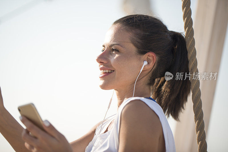 年轻女子手持手机，使用耳机