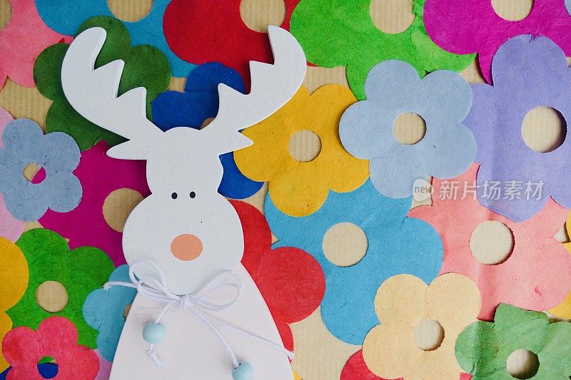 白色的木鹿和彩色的纸花背景