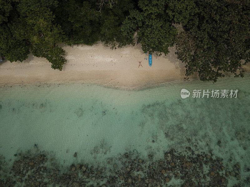 无人机视角鸟瞰年轻女子放松在热带海滩天堂，拍摄在菲律宾偏远的岛屿。人们旅行度假田园的概念。埃尔尼多,巴拉望