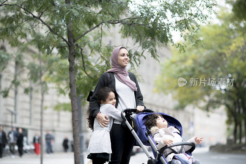 一位年轻的穆斯林母亲正要和她的家人过马路