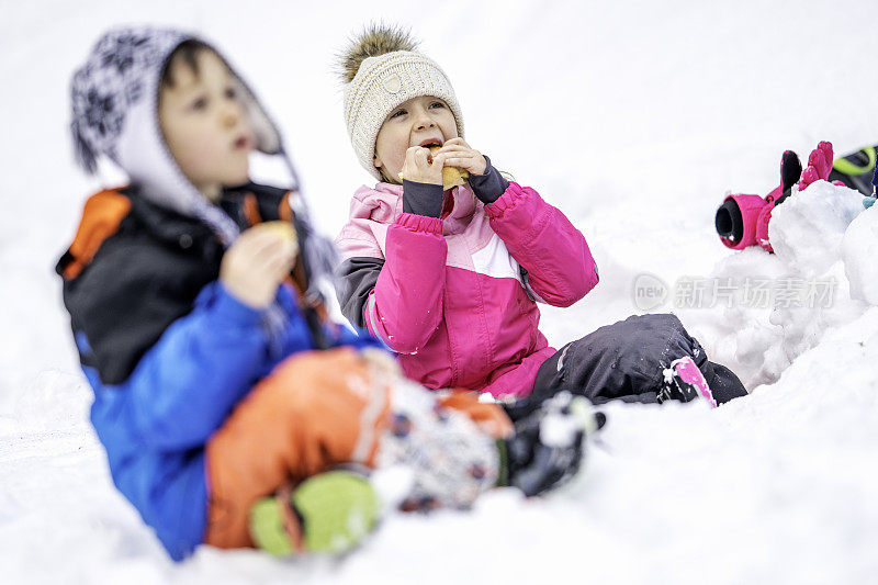 孩子们坐在雪地里吃零食