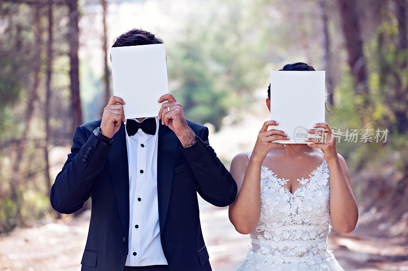 新婚夫妇用白纸遮住脸。