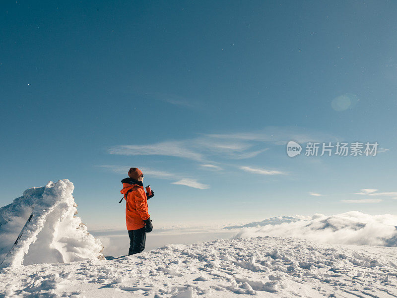 女性高山攀登者在冬季日出时在高海拔的山峰上喝咖啡