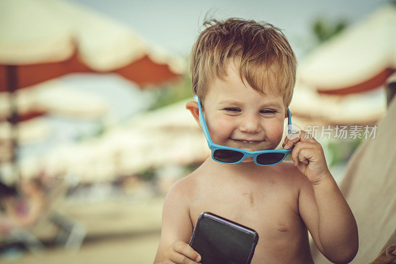快乐的小男孩在海滩上打电话