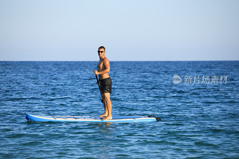 海滩度假小伙子们站起来划桨板SUP，海夏天的爱