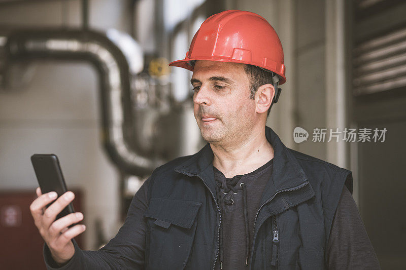 在工厂里使用手机的男性技术员