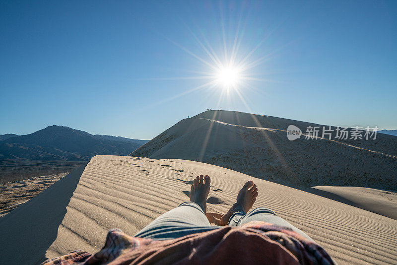 女性日落时在沙丘上放松的个人视角;脚视图;人们旅游度假放松的概念