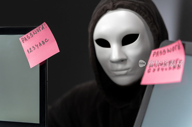 戴面罩的黑客夹在两台笔记本电脑之间