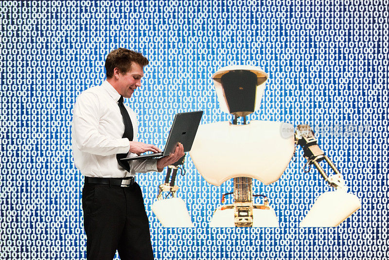 一名男性工程师正在展示他的机器人技术并使用他的笔记本电脑
