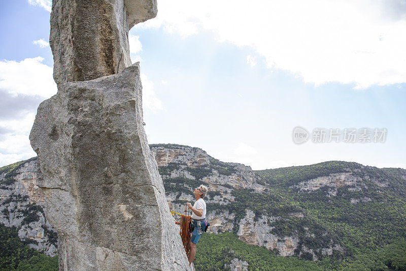 攀岩者从岩石尖顶探出身子，计划下一步行动