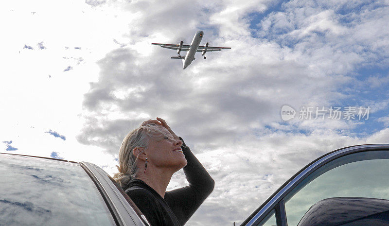 当飞机在上空起飞时，一个成熟的女人抬起头