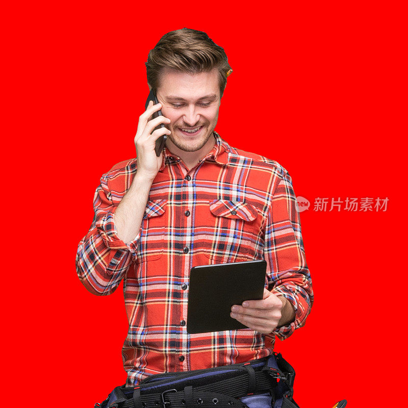 一名男性建筑工人站在彩色背景前，穿着格子衬衫，手持锤子，使用数码平板电脑