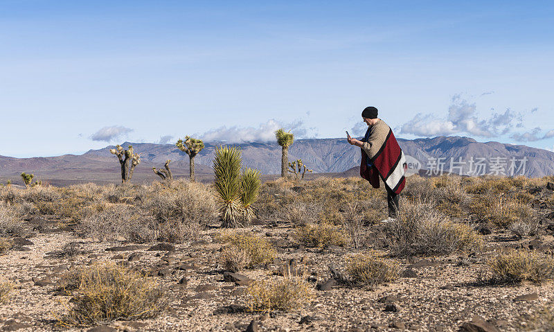 一个成熟的女人，一名游客，在加利福尼亚的沙漠中拍摄生长的yukka。