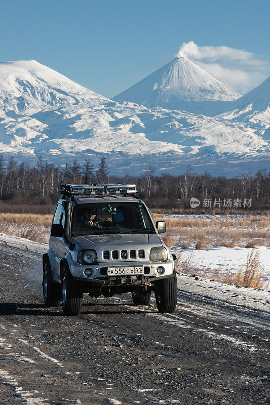 日本SUV铃木吉姆尼沿路行驶，背景是美丽的冬季风景旅游目的地——活火山克鲁切夫斯卡