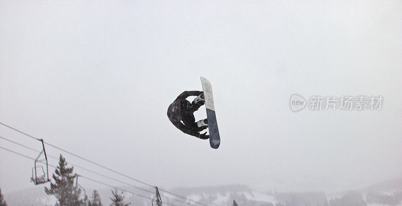 一个滑雪板在完整的冬季装备试图在一个跳跃在Eldora滑雪度假村附近的博尔德，科罗拉多州雪，阴天“开关540陈腐抓取”把戏