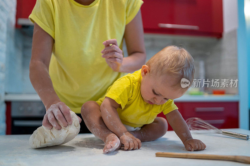 妈妈和儿子正在准备早上一起做饼干的面团。孩子在扔面粉，很高兴。