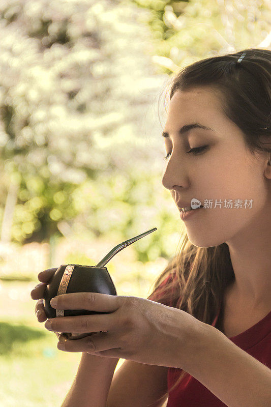 一个女人正要喝一杯“Mate”，这是一种在阿根廷，巴西，巴拉圭和乌拉圭很受欢迎的饮品，用巴拉圭茶调制而成。