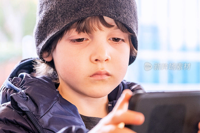 沉思的小男孩在看智能手机