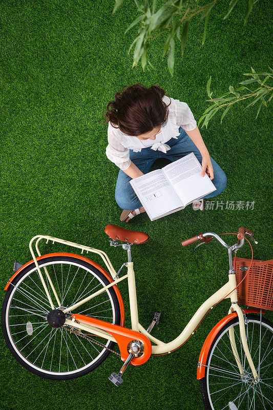 坐在草地上看书的青年女人