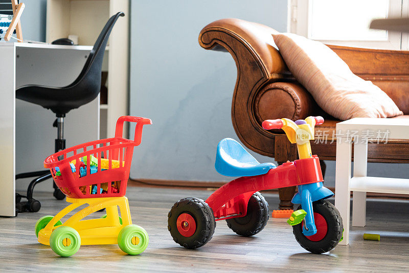 客厅里的彩色三轮车和玩具购物车