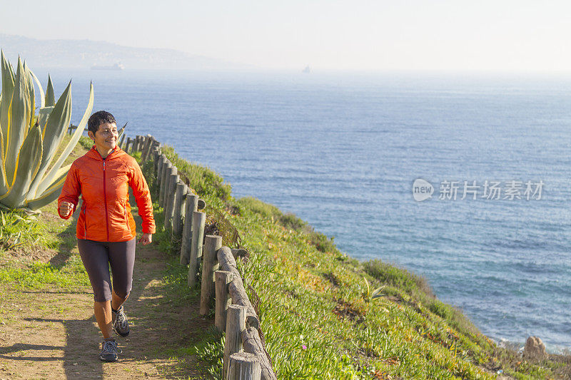 拉丁成年女子沿着海边的木板路跑步