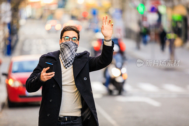 年轻的商人戴着保护用的大手帕，独自站在空荡荡的街道上等公共汽车或出租车。病毒大流行或污染概念。