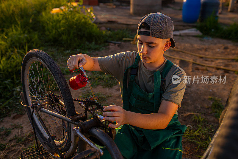 一个十几岁的男孩，一个户外自行车修理店的实习生，用机油润滑自行车的链条