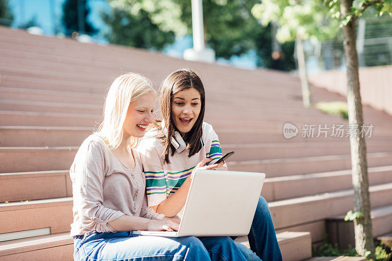 两个女孩使用笔记本电脑，在网上玩得很开心