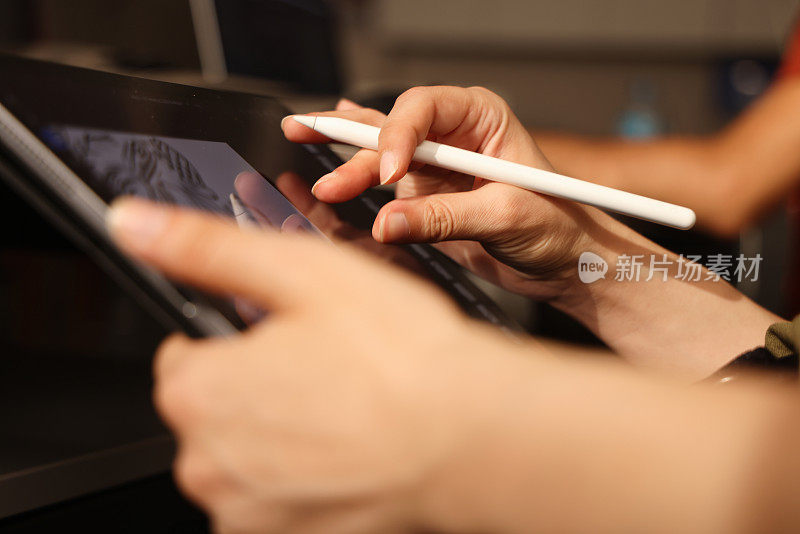 特写女性手使用数字笔在数字平板屏幕上书写