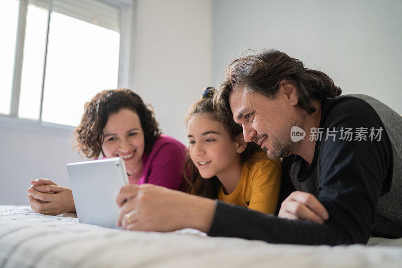家人在家里的床上用电子平板电脑看东西