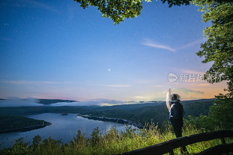 人们在美丽的风景中拍摄和仰望银河