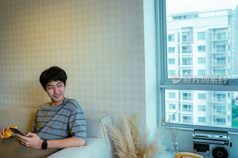 年轻的亚洲男子在家里用智能手机上的健康计划移动应用程序