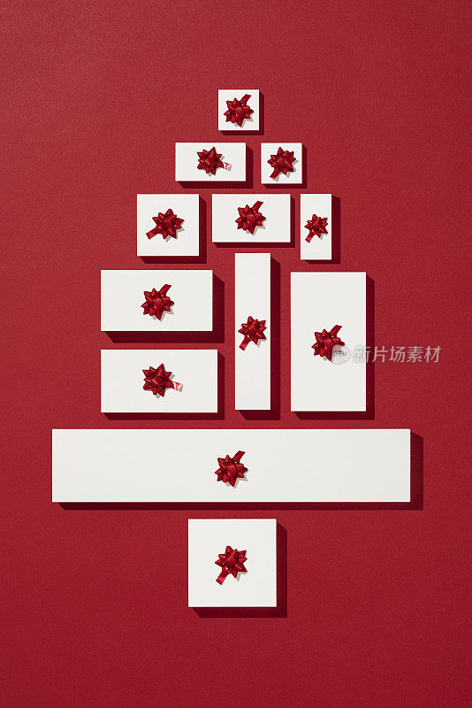 白色的礼品盒在红色的背景上排列成圣诞树