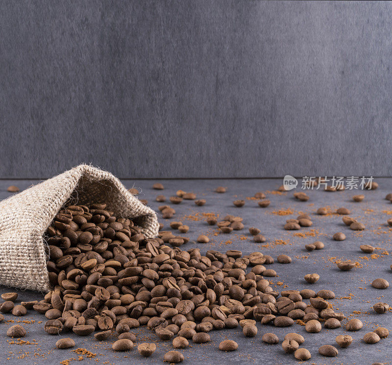土耳其咖啡豆从粗麻袋中溢出。到处都是咖啡豆。背景是灰色的。