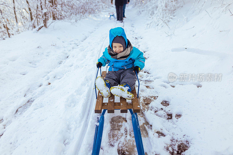可爱的小男孩在雪橇上，在大自然的冬天