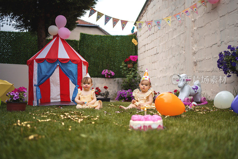 双胞胎姐妹在草地上玩在他们的第一个生日聚会