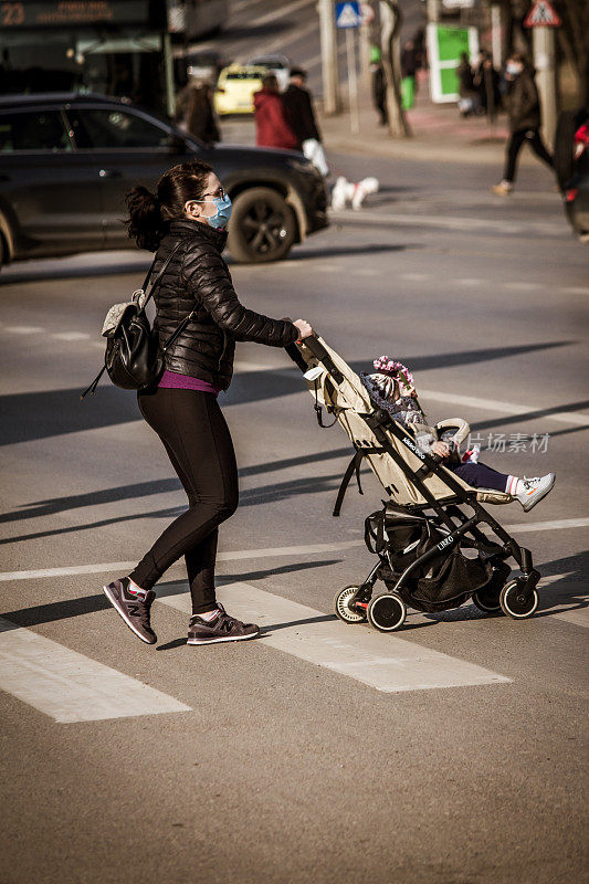 一位年轻女士推着婴儿车过马路